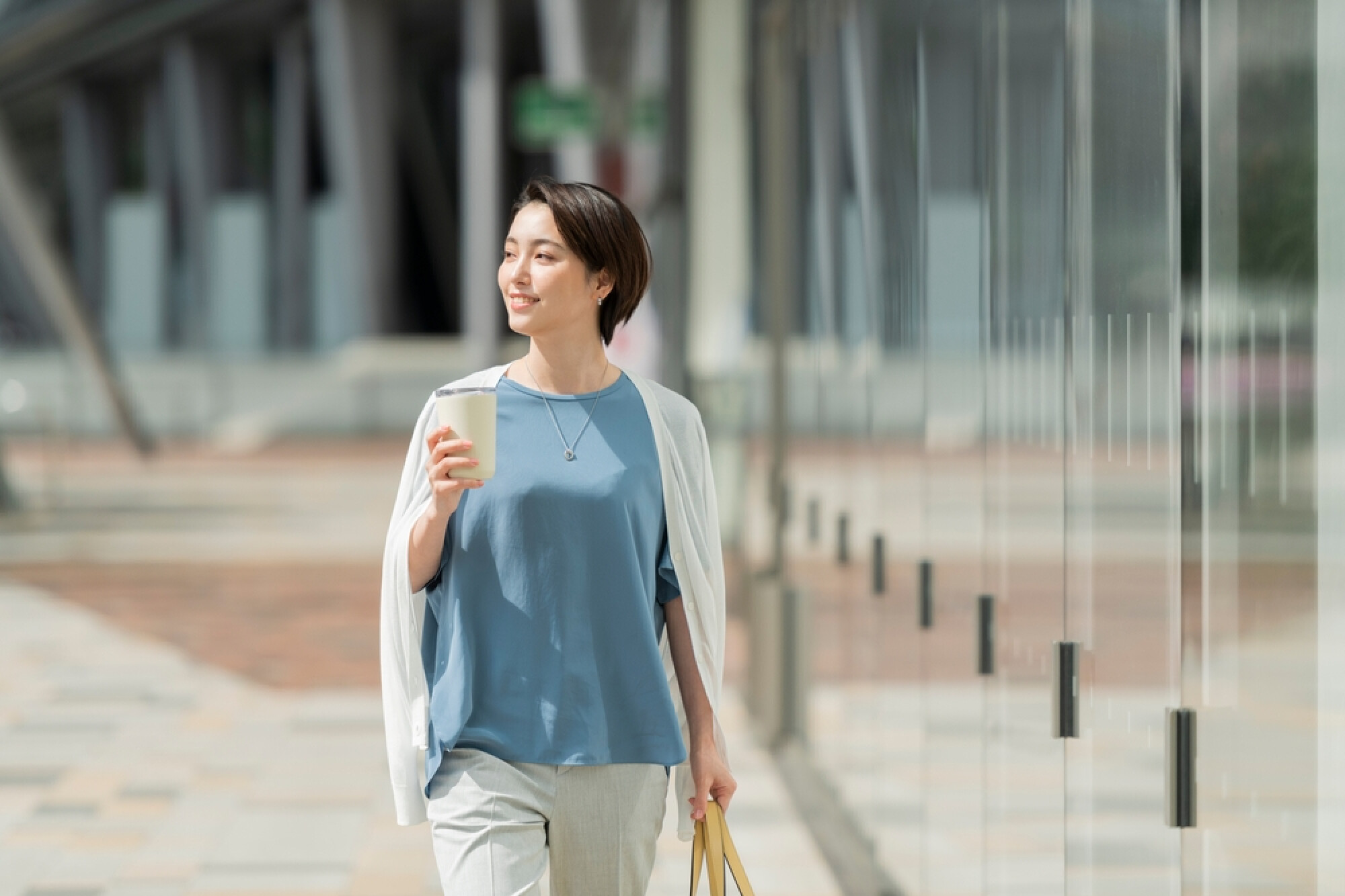 女人一边拿着水杯一边散步，展示出饭后散步帮助消化的健康生活方式。