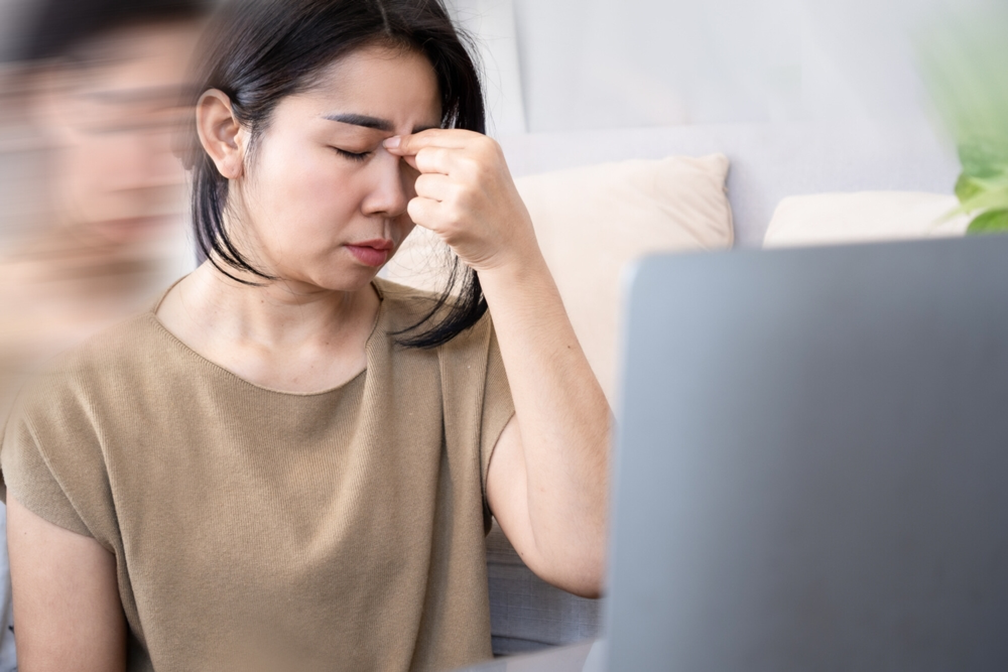 一名女子用手按住鼻樑，展示了過度的壓力會對身心造成負面影響