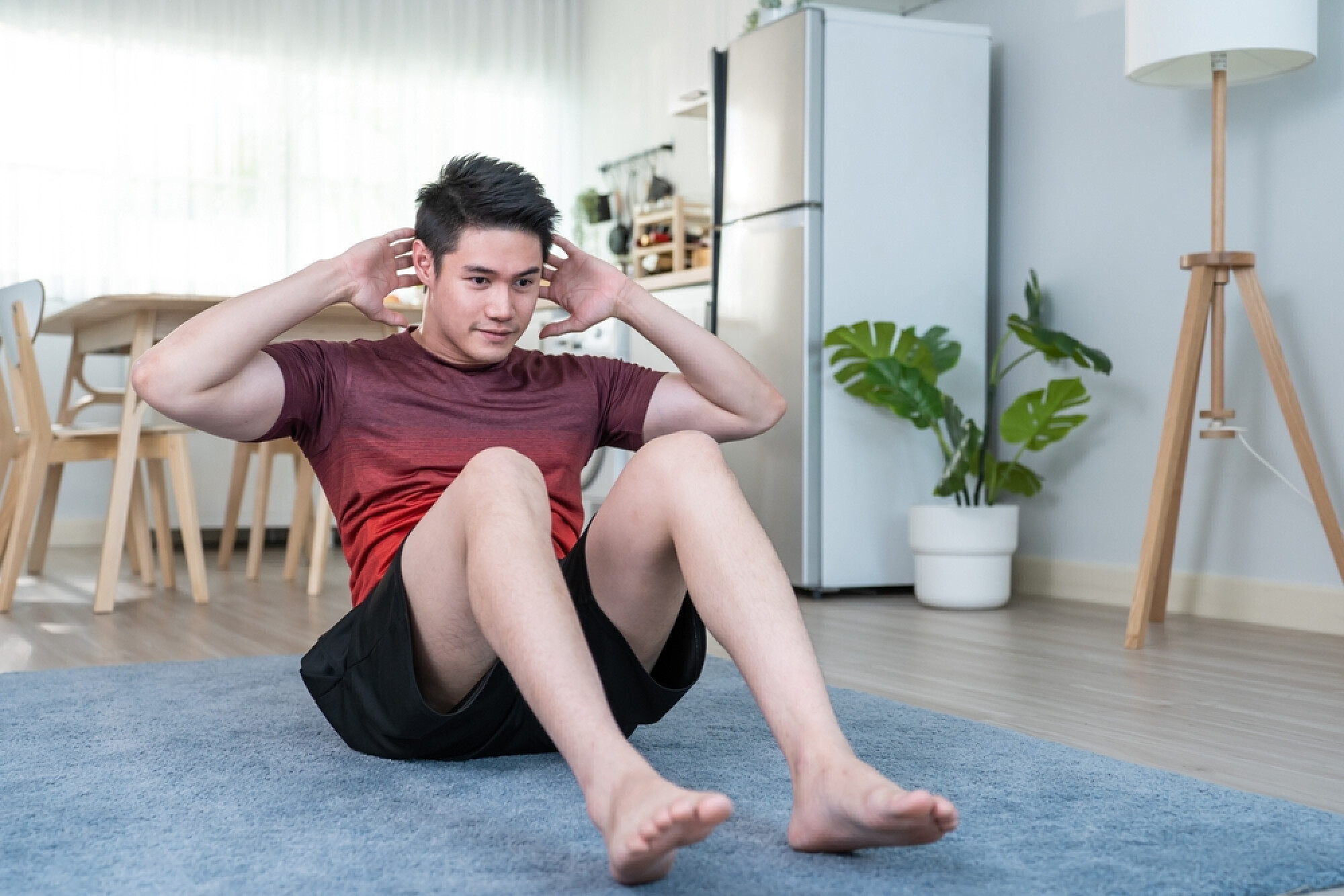 一名男子在家中做仰臥起坐，展示徒手健身可以鍛鍊腹部核心肌群。