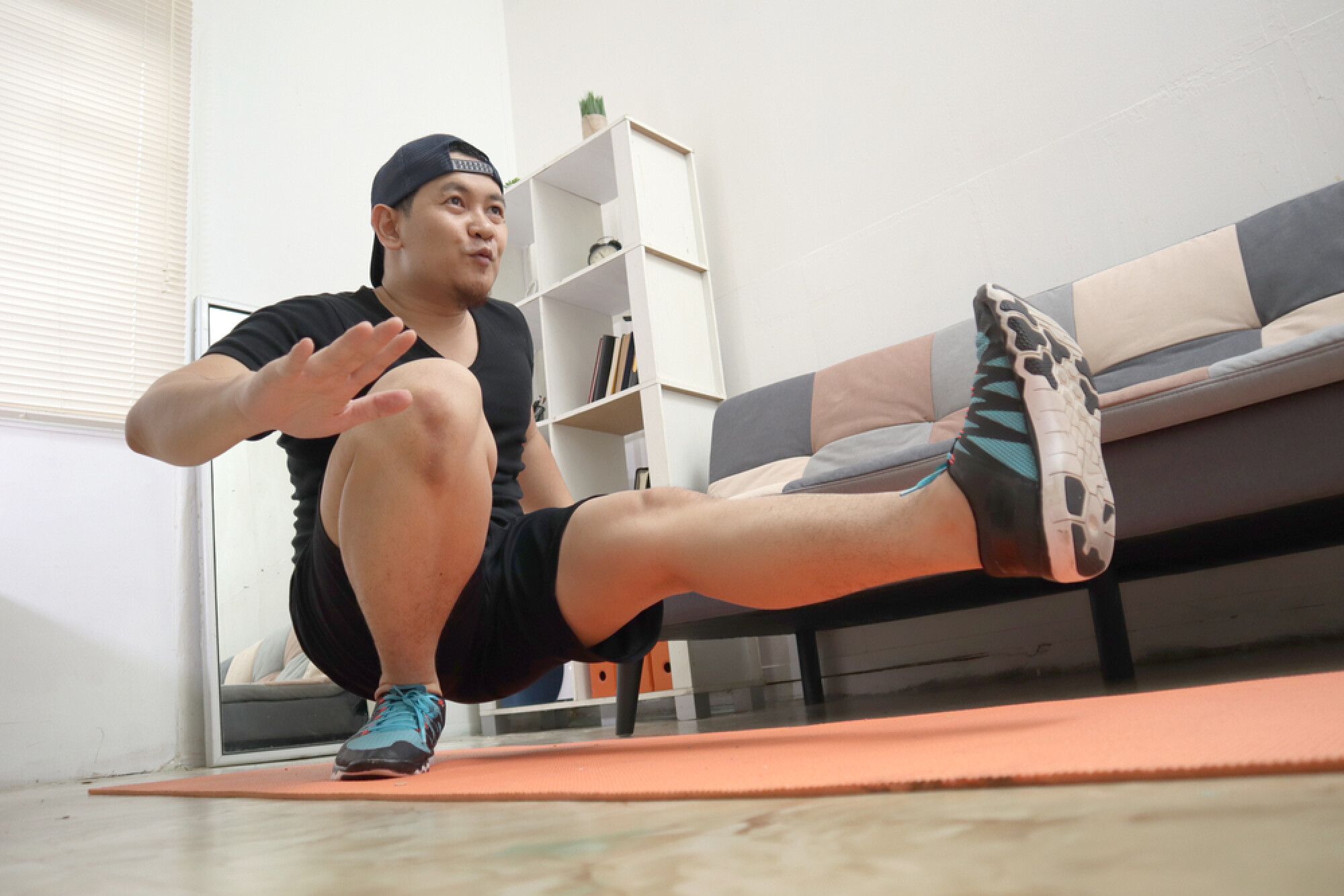 一名男子在家中的瑜珈墊上運動，展示出單腿深蹲的高難度動作