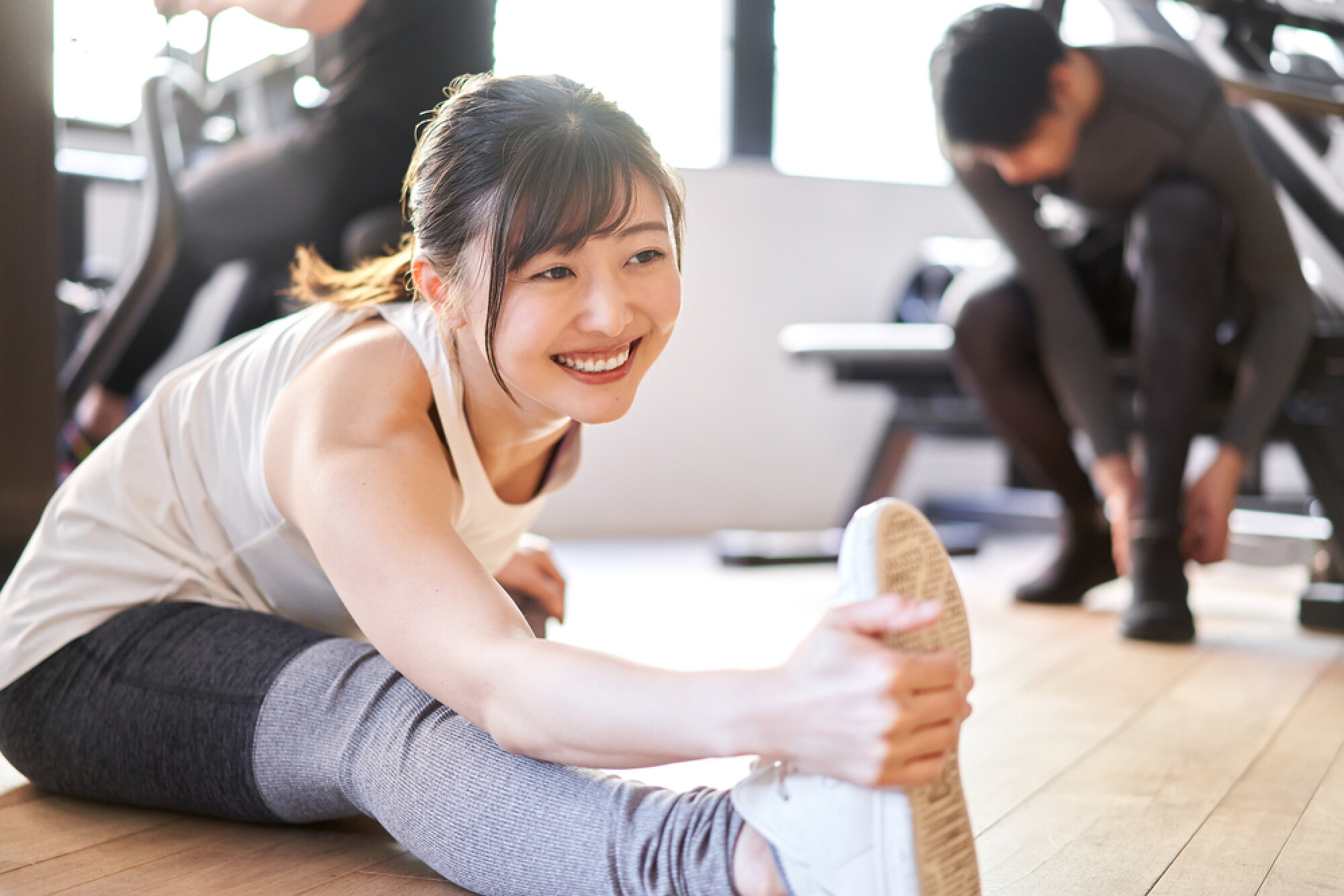 一名女子臉帶微笑做腿部拉筋，展示了運動前後拉筋的好處