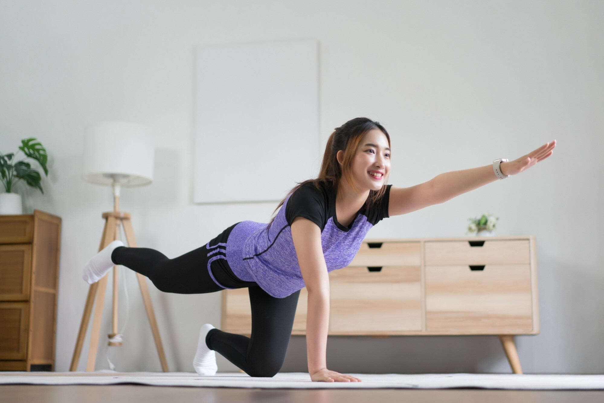  一名女子在室內瑜珈墊上做鳥狗式動作，展現普提拉能改善平衡感，有助提升身體協調能力