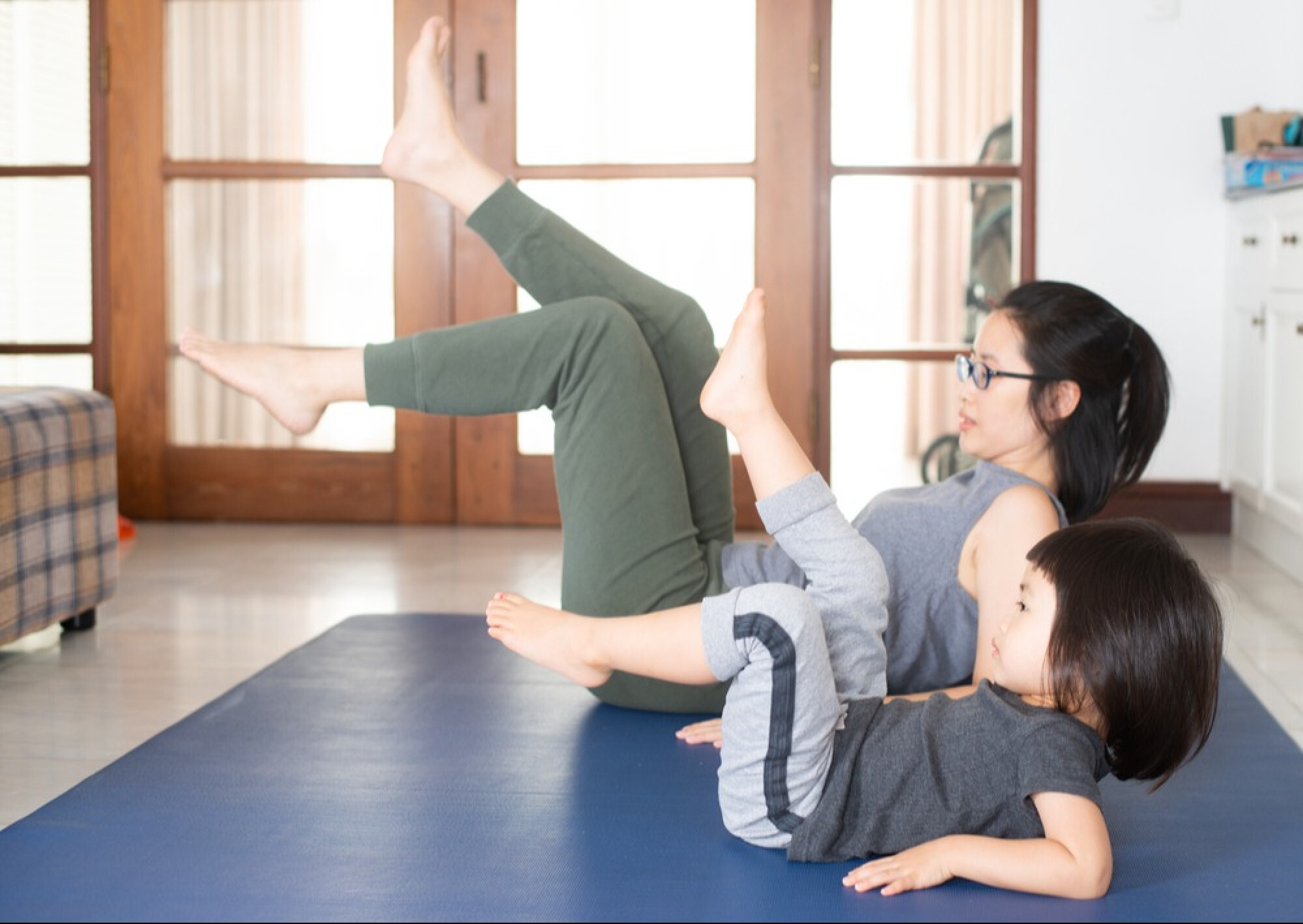 一名女子與小童在瑜珈墊上運動，展現普拉提適合男女老少練習