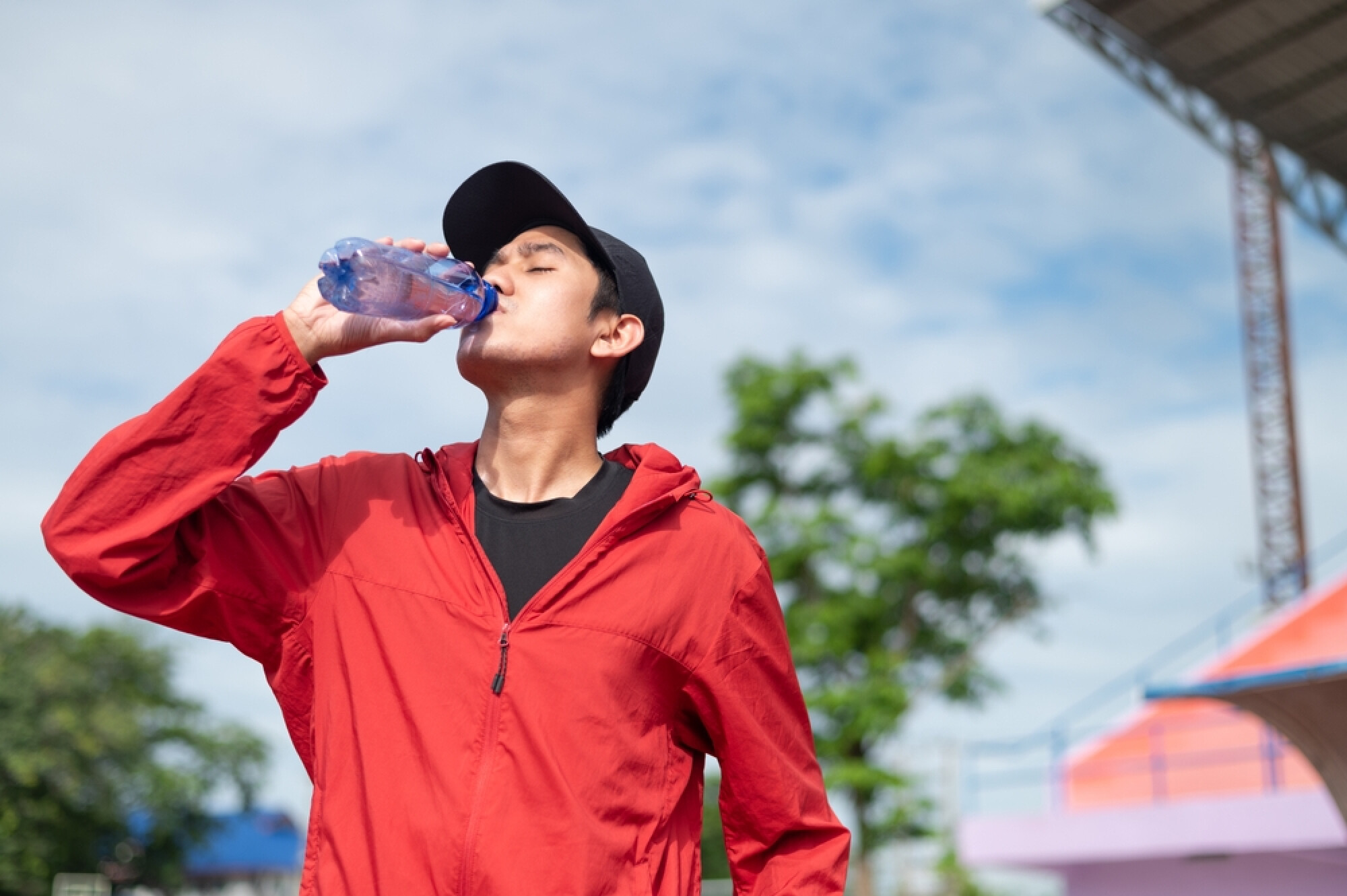  男子穿上運動服在室外喝水，展現運動後要補充水份。