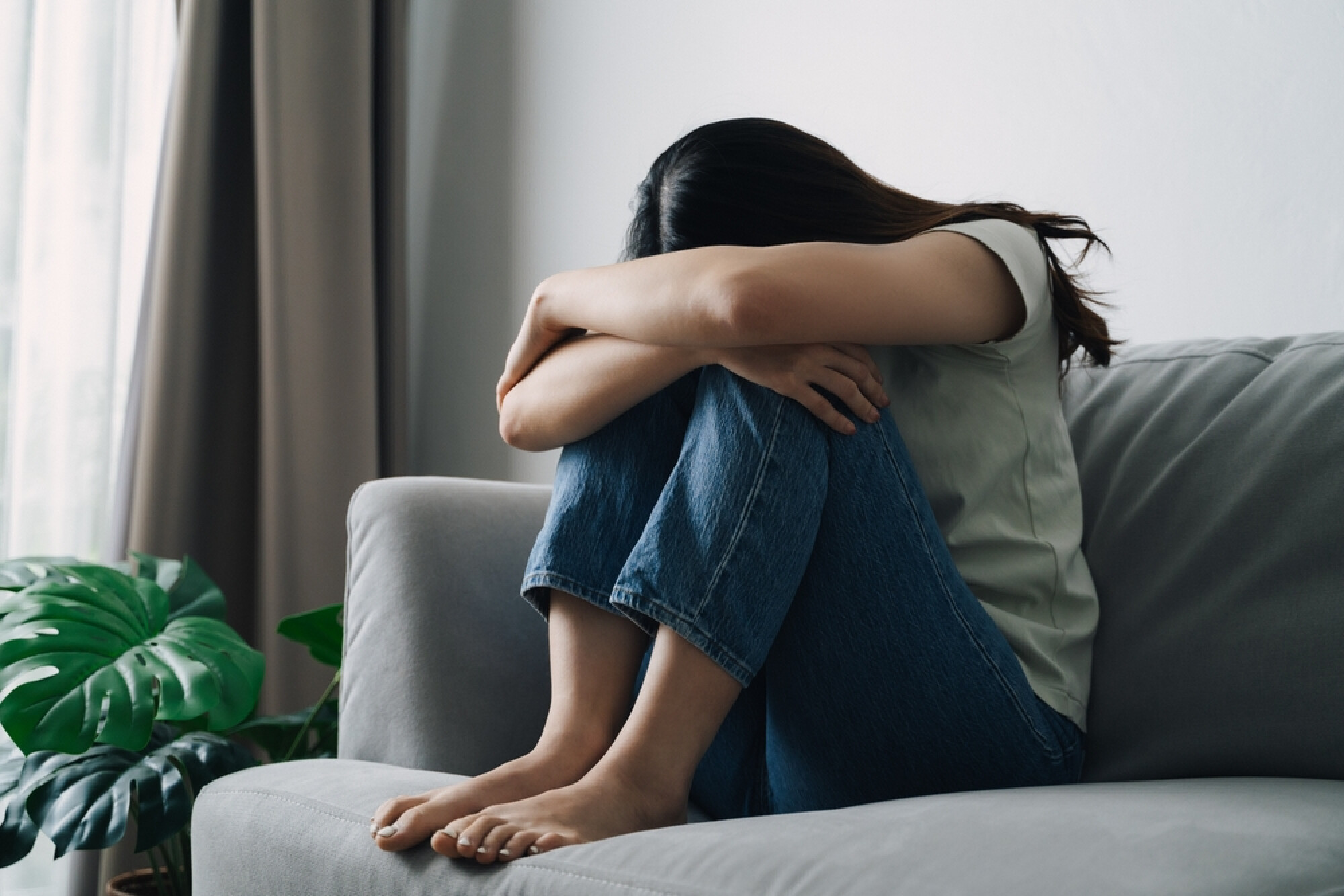 一名女子抱膝坐在梳化上，展現了都市人生活壓力繁重，容易情緒低落