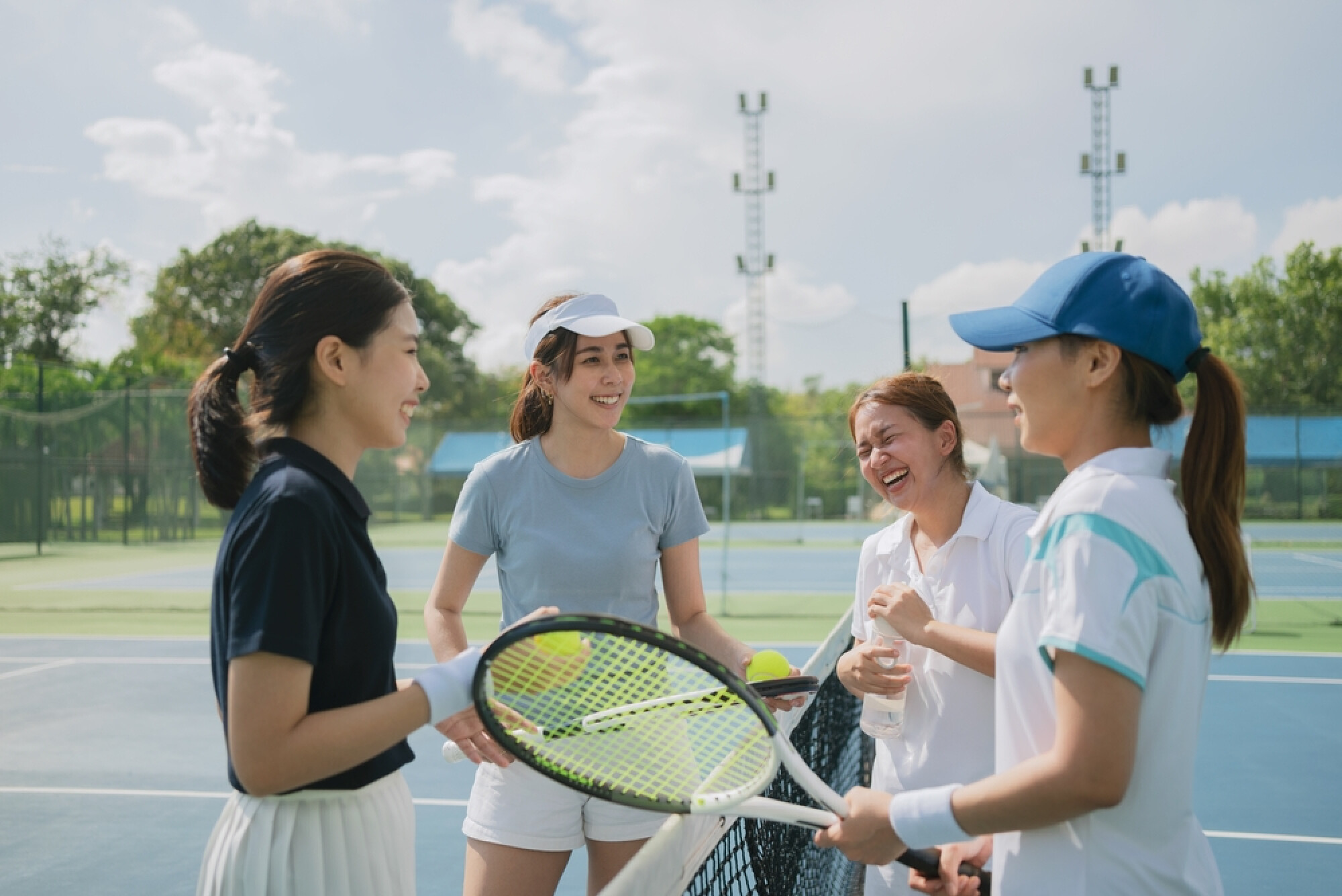 4位女子在網球場談笑甚歡，展示與好友一起運動更愉快。