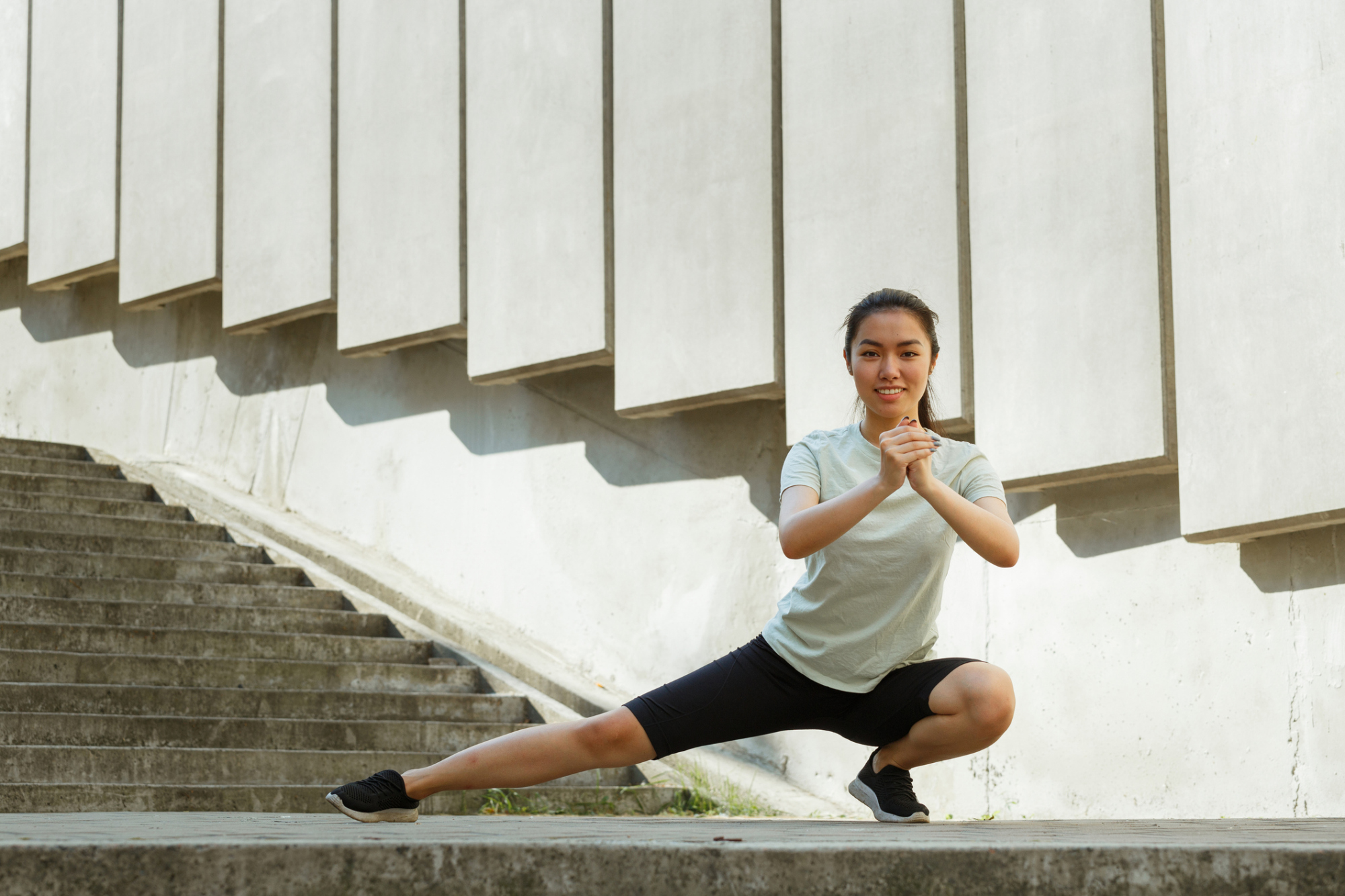 iStock-1345500635.jpg 女子示範側向弓箭步熱身動作,重心向一側移動下蹲,伸展大腿內側內收肌群。